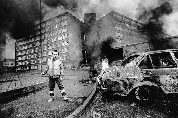 Boy and flaming car outside Divis flats.