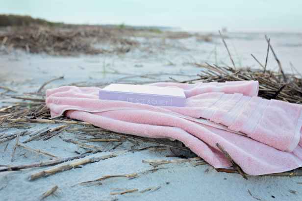 book on pink textile on sand during day